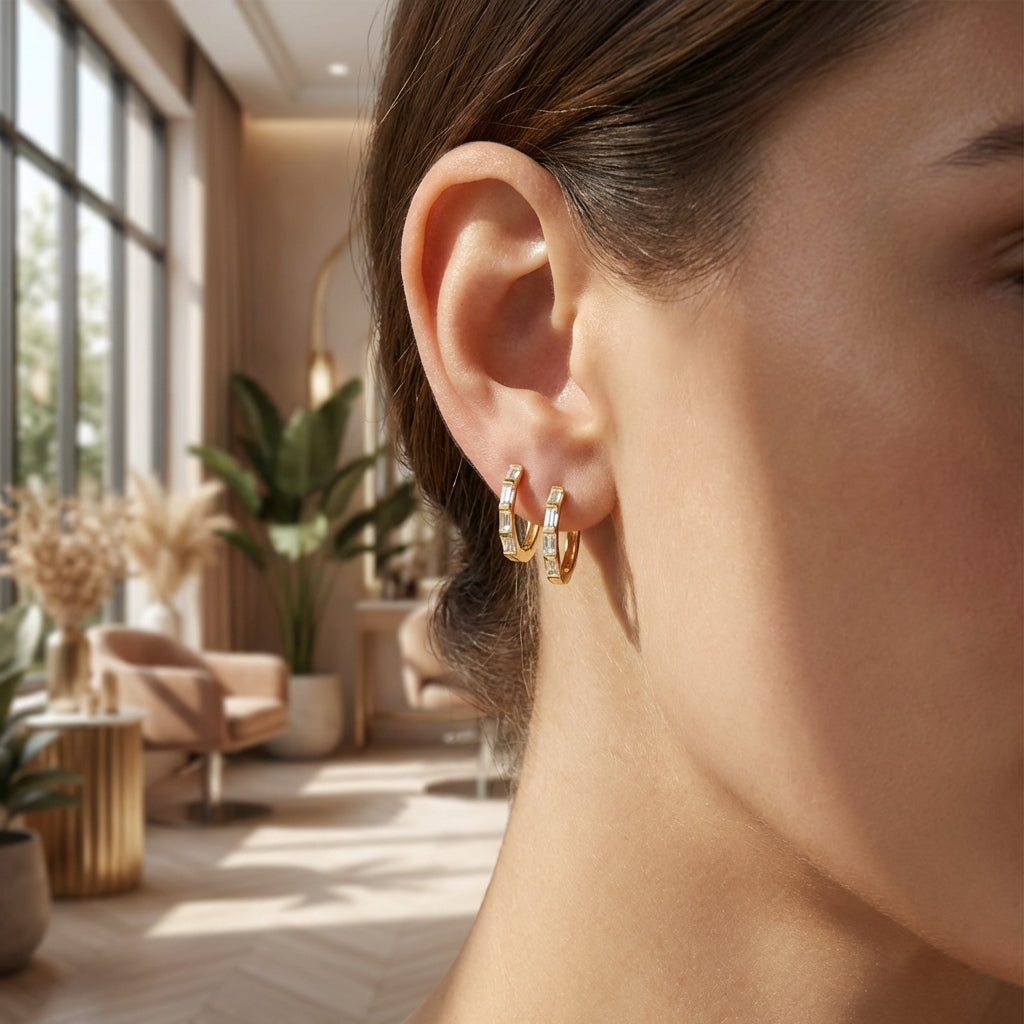 Model wearing 14K gold baguette diamond huggie earrings in a natural indoor setting, showcasing their subtle elegance and daily wear suitability.