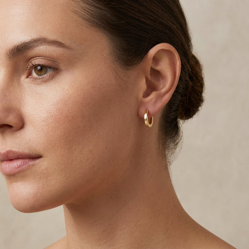 Full-body shot of woman wearing discreet 12mm 14k gold huggie hoops, styled minimalistically with soft lighting on a neutral background.