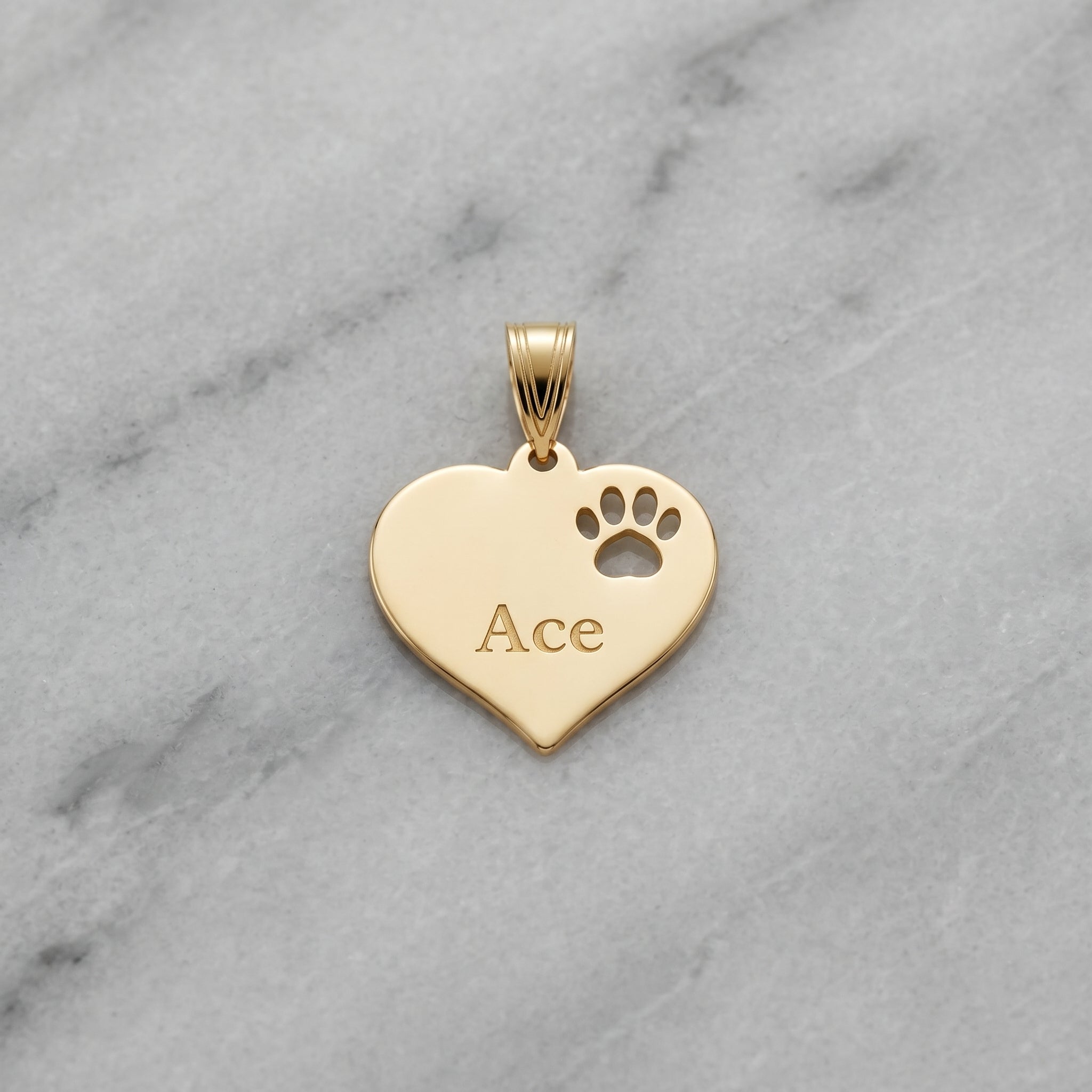Polished 14K gold paw print pendant with diamond details displayed on marble, emphasizing craftsmanship and micro-details.