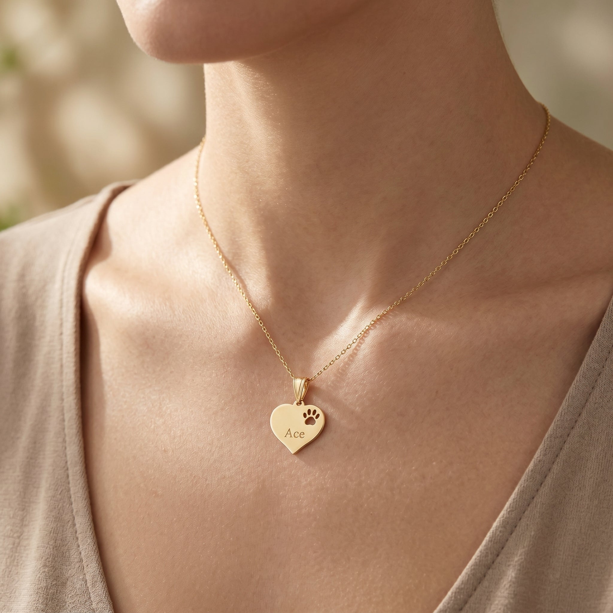 Model wearing delicate 14K gold paw print charm necklace on a slender chain, showing size and detailed micro-texture.